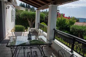 a patio with a glass table and chairs on a balcony at Emmy villa paleokastritsa in Paleokastritsa