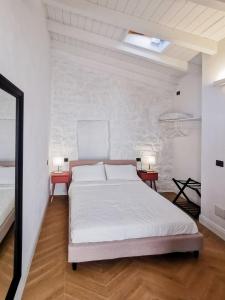 a white bedroom with a bed and two tables at Affittacamere Faber in Tempio Pausania