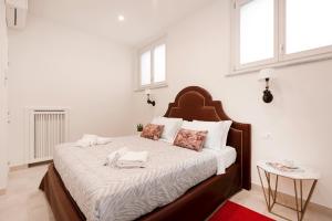 una camera da letto con un grande letto con lenzuola e cuscini bianchi di Divo Apartments - Spanish Steps a Roma