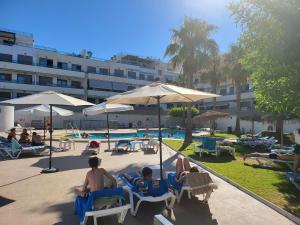 a group of people sitting in lawn chairs near a pool at La Paz del Mediterráneo in Garrucha