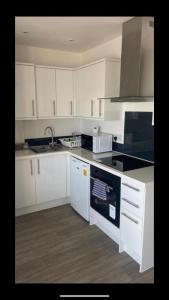 een keuken met witte kasten en een fornuis met oven bij Penthouse Apartment with seaviews in Walton-on-the-Naze