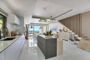 a kitchen with white walls and white floors and a staircase at BEACHSIDE VILLA - CLOUD 9 - at BAYSIDE LUXURY VILLAS Samrong Bay Beach, 3 BED 4 BATH, SALT WATER POOL, SEA and SUNSET VIEWS, only 200m walk to the Beach in Amphoe Koh Samui