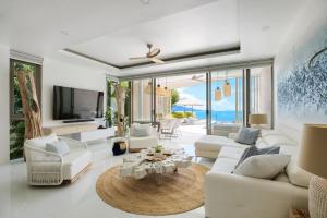 a living room with white furniture and a view of the ocean at BEACHSIDE VILLA - CLOUD 9 - at BAYSIDE LUXURY VILLAS Samrong Bay Beach, 3 BED 4 BATH, SALT WATER POOL, SEA and SUNSET VIEWS, only 200m walk to the Beach in Amphoe Koh Samui