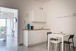 eine Küche mit weißen Schränken und einem Tisch und Stühlen in der Unterkunft Sulla Valle in Agrigento + 4 Fotos