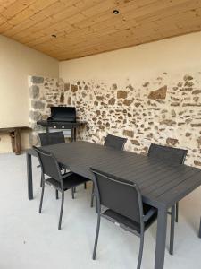- une table et des chaises noires dans une pièce dotée d'un mur en pierre dans l'établissement Gîte de la Foye - Le Jasmin, à Combrand