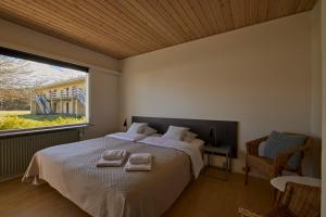 una camera da letto con un letto grande con due asciugamani sopra di Strandhotel Klitrosen a Fjerritslev