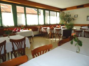 a dining room with tables and chairs and windows at Hotel de l'Union in Orsières