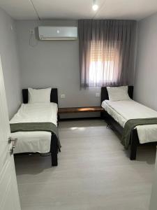 Zimmer mit 2 Betten und einem Fenster in der Unterkunft Menachem's Apartment in Bet Scheʼan