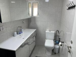 Baño blanco con aseo y lavamanos en Menachem's Apartment, en Beit She'an
