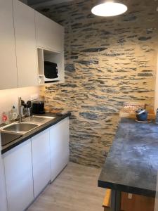 a kitchen with white cabinets and a stone wall at La Maison du Cocher - Studio climatisé en Hypercentre in Angers