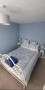 um quarto com uma cama branca e paredes azuis em Beautiful 1 bedroom cottage with courtyard. em Kent