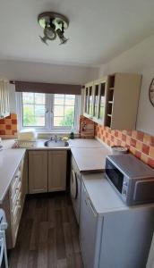 a kitchen with a sink and a microwave at Beautiful 1 bedroom cottage with courtyard. in Kent