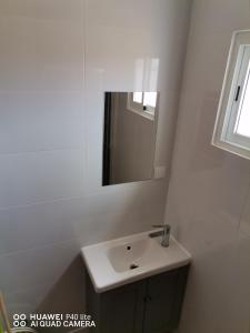 uma casa de banho branca com um lavatório e um espelho em Lourisol em Lourinhã