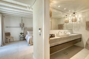 a bathroom with a large sink and a bedroom at Mykonos Panormos Villas in Mykonos