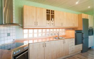 a kitchen with wooden cabinets and a black refrigerator at Lovely Apartment In Gotlands Tofta in Västergarn