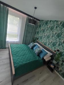 a bedroom with a bed with green sheets and blue pillows at Apartament Bernata-Śródka in Poznań