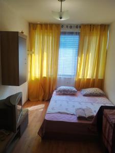 a bedroom with two beds and a tv and curtains at Апартмент Паисий 15 in Varna City