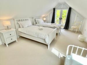 ein weißes Schlafzimmer mit zwei Betten und einem Fenster in der Unterkunft Rye Court Cottages in Helmsley