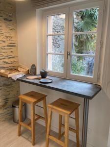 a kitchen with a counter with two stools and a window at La Maison du Cocher - Studio climatisé en Hypercentre in Angers