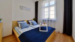 sypialnia z łóżkiem z niebieską pościelą i oknem w obiekcie ARGENTIS RYNEK RATUSZ IV we Wrocławiu