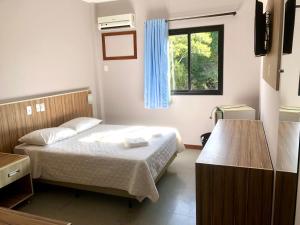 a small bedroom with a bed and a window at Hotel Rinkao in Cachoeiro de Itapemirim