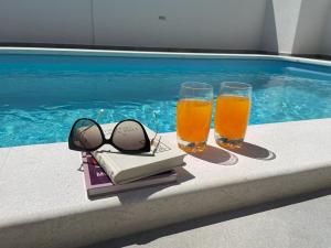 2 bicchieri di succo d'arancia e libri accanto alla piscina di Apartment Edita Plano Trogir a Plano