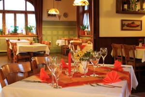 una sala da pranzo con tavolo, tovaglioli rossi e bicchieri da vino di Gasthof Seerose a Radolfzell am Bodensee