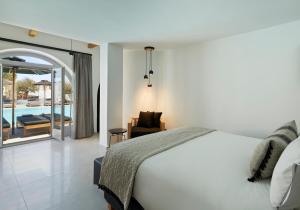 een slaapkamer met een bed en uitzicht op een zwembad bij Kalisti Hotel & Suites in Fira