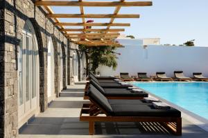 a row of chaise lounge chairs next to a swimming pool at Kalisti Hotel & Suites in Fira