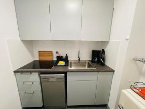 a small kitchen with white cabinets and a sink at Apartment Strandkorv für 2-4 Personen mit Pool in Dahme