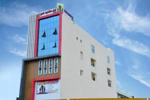 a tall building with a red and white at Thai Residency - Opp to Bus Stand in Dhārāpuram