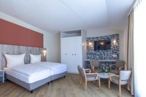 una camera d'albergo con un letto, un tavolo e delle sedie di Michels Gästehaus Meerzeit a Norderney