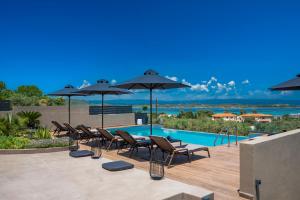 a patio with chairs and umbrellas next to a pool at Anmian Suites in Vourvourou