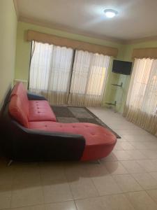 ein rotes Sofa im Wohnzimmer mit TV in der Unterkunft Villa Victoria in La Romana