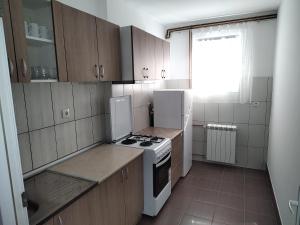 una cocina con electrodomésticos blancos y armarios marrones en Apartman Anastasija en Surčin