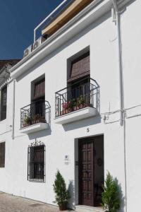 un edificio blanco con 2 balcones y una puerta en La casa del Mejorato, en Priego de Córdoba