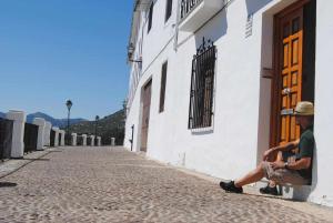 un hombre sentado en un banco junto a un edificio en La casa del Mejorato, en Priego de Córdoba