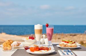 a table with plates of food and drinks on the beach at Universal Hotel Cabo Blanco - Adults Only in Colònia de Sant Jordi