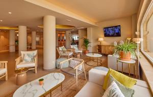 コロニア・サン・ジョルディにあるユニバーサル ホテル カボ ブランコ 大人専用の白い家具と壁掛けテレビが備わるロビー