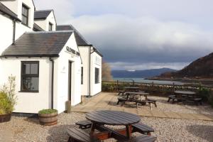 a patio with picnic tables and a view of the water at Glenuig Inn in Lochailort