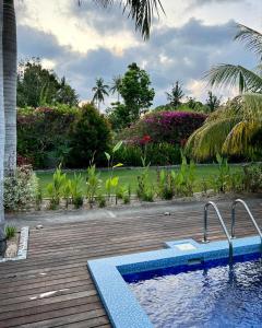 a swimming pool on a wooden deck next to a yard at Burudika Bungalows in Selong Belanak