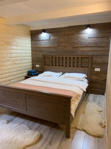 a bedroom with a large bed with a wooden wall at Lucomi Chalet - For groups - 5 bedrooms in Poiana Ţapului