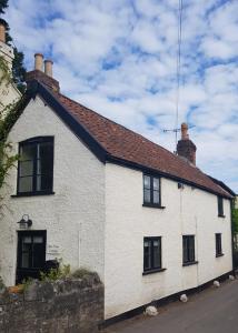 a white house with black windows and a roof at Bay Tree Cottage in Langford