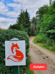 Ein Schild mit einem roten Fuchs auf einer unbefestigten Straße. in der Unterkunft Jägerhaus in Nossen