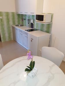 eine Küche mit einem weißen Tisch mit einer lila Blume in einer Vase in der Unterkunft Apartments Vidakovic in Ugljan