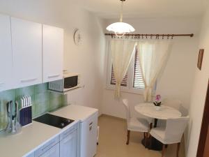 a kitchen with a small table and a white kitchen at Apartments Vidakovic in Ugljan