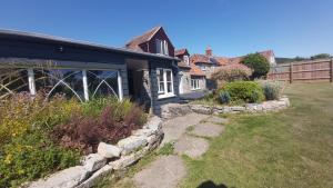 una casa negra con una pared de piedra junto a un patio en Bluebell House 5 Star Holiday Let en Somerton