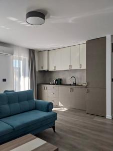 a living room with a blue couch and a kitchen at Modern and New Apartments in North of Timisoara - PNM Residence in Dumbrăviţa