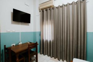 a room with a curtain and a table and a television at HOTEL LUNXHERIA in Gjirokastër