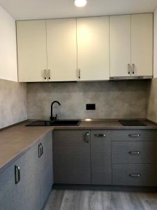 a kitchen with white cabinets and a sink at Modern and New Apartments in North of Timisoara - PNM Residence in Dumbrăviţa